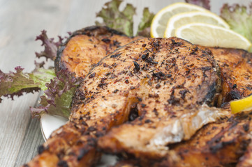 Fried salmon on a white plate decorated with lemon and salad