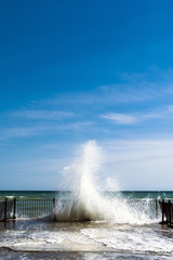 Sea water splashes at old pier on sunny day