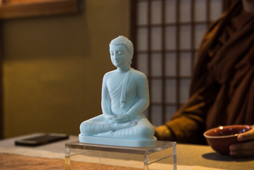 White Buddha statue sitting on the table and a monk