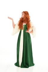 Fototapeta premium full length portrait of red haired girl wearing long green medieval gown. standing pose, isolated on white studio background.