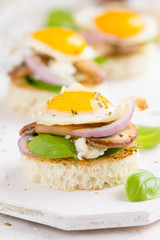 Canapes with fried mushrooms, quail egg, soft cheese and basil, beautiful appetizer for home party or event