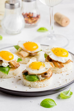 Canapes with fried mushrooms, quail egg, soft cheese and basil, beautiful appetizer for home party or event