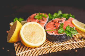 Salmon steaks with lemon and spices close up view.