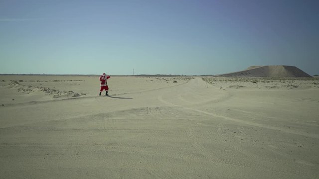 Santa Claus with sack walks on sand, found asphalt road in desert, comes, coming to town for Christmas at summer in Africa, UAE