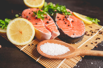 Two salmon steaks with lemon, pepper and salt. View from above.