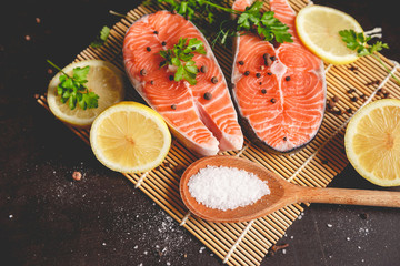 Two salmon steaks with lemon, pepper and salt. View from above.