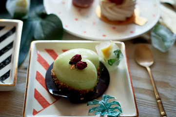 Pistachio mousse cake in the fishing Culinary art. On striped graphic saucers
