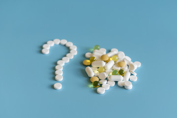 medicine pills, tablets and capsules symbol question mark on a blue background. White Tablets On Blue Background As Question Mark