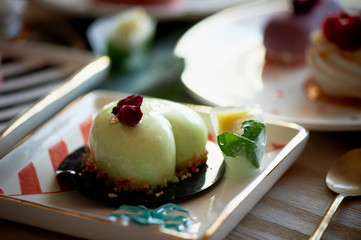Pistachio mousse cake in the fishing Culinary art. On striped graphic saucers
