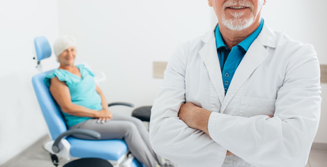 smiling doctor standing before elderly patient in medical office