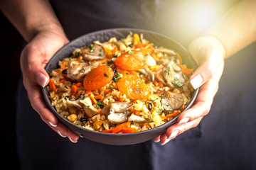 The girl cook holds a plate with a vegetarian plov, Uzbek traditional cuisine