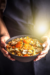 The girl cook holds a plate with a vegetarian plov, Uzbek traditional cuisine
