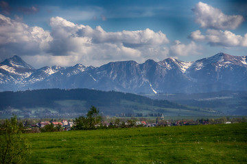 Rural buildings with a church tower on the background of the Tatra Mountains