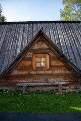 An old, wooden highlander's cottage with a small window and a wooden bench standing by the window