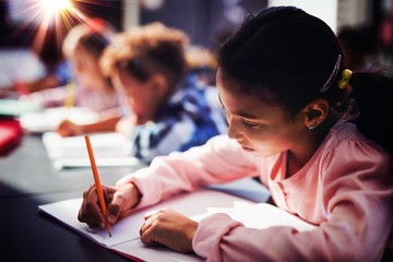 Attentive schoolgirl doing her homework in classroom