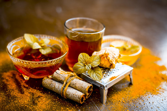 Ancient ayurveidc home remedy for common cold: Grated ginger, warm water, cinnamon powder, honey, and lemon juice in a transparent glass on wooden surface.