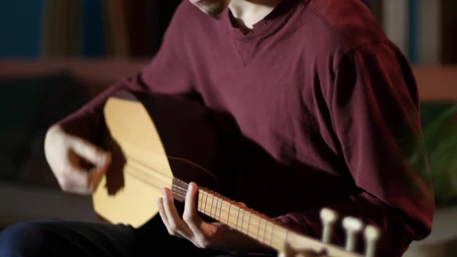 Closeup on the fingering on a beautifully lit saz being performed by a young man.