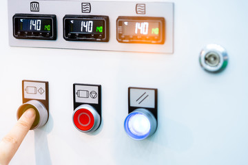 Engineer's hand push green button to open temperature control machine. Temperature control panel cabinet contain digital screen display for temperature gauge. Heat control in industrial factory.