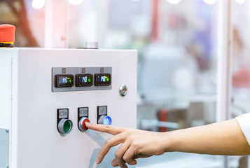 Engineer's hand push red button to shutdown temperature control machine. Temperature control panel cabinet contain digital screen display for temperature gauge. Heat control in industrial factory. - obrazy, fototapety, plakaty