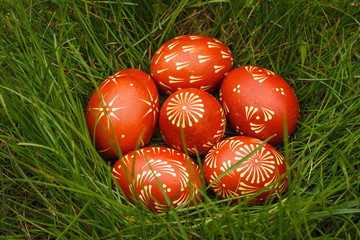 Ukrainian painted easter eggs of red color lie in the grass. Close-up