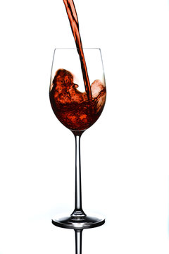 cherry red wine being poured in tall wine glass with splash and bubbles