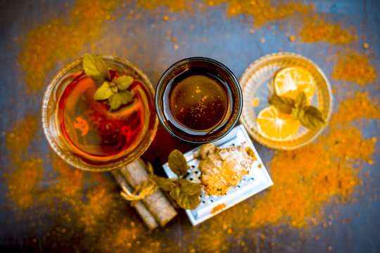Ancient ayurveidc home remedy for common cold: Grated ginger, warm water, cinnamon powder, honey, and lemon juice in a transparent glass on wooden surface.