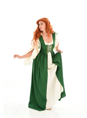 full length portrait of red haired girl wearing long green medieval gown. standing pose, isolated on white studio background.