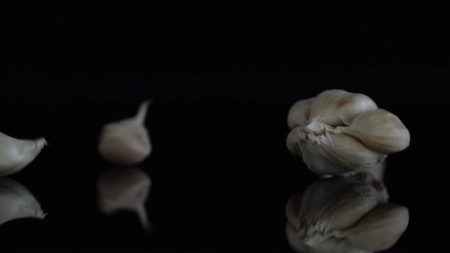 Garlic fall slow motion on the black background. The concept of cooking and agricultural crops.