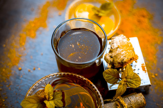 Ancient ayurveidc home remedy for common cold: Grated ginger, warm water, cinnamon powder, honey, and lemon juice in a transparent glass on wooden surface.