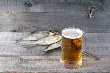 A mug of  light beer and dry fish on a wooden background.