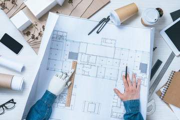 cropped image of male architect with prosthetic arm drawing by pencil and ruler on blueprint