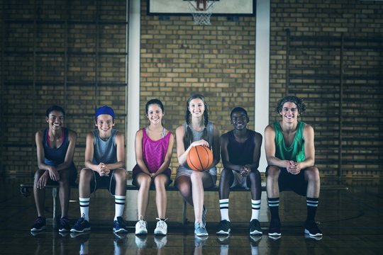 High School Kids Sitting On A Bench In Basketball Court