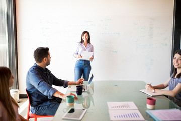 Obraz premium Smiling woman giving presentation to her team