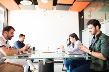Business group with phones distracted from meeting