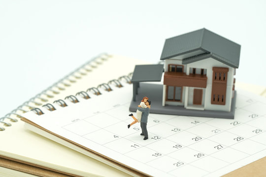 ouple Miniature 2 people standing on Calendar and A model house model is placed on a calendar and pen. as background property real estate concept with copy space for your text or  design.
