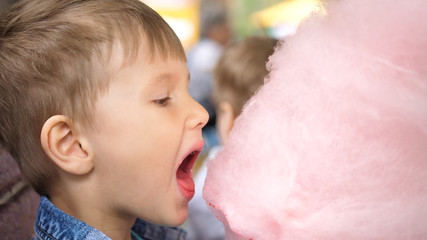 Baby eating cotton candy in the Park. Sweet and airy dessert. The day of the birth of the child.