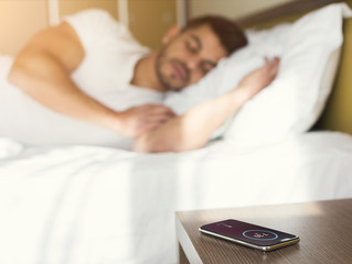 Man sleeping in bed while hearing alarm clock