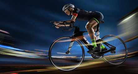 Sport background. Athletic woman cycling road bike in the evening. Dramatic view of the night city.