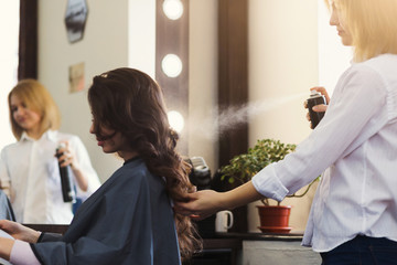 Hairdresser making curly hairstyle at beauty salon