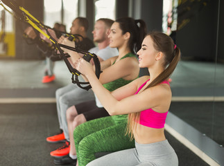 Group performing TRX training in gym