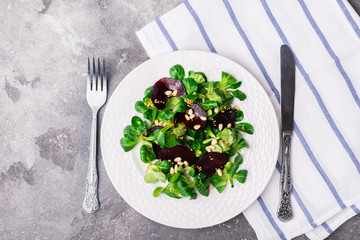 Vegetarian salad of fresh sprouts of a young green salad with corn and beets in a white plate. The concept of a healthy diet. Flat layout; view from above. Copy space.