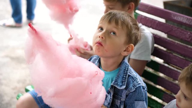 Children eat cotton candy in the Park. Sweet and airy dessert. The day of the birth of the child.