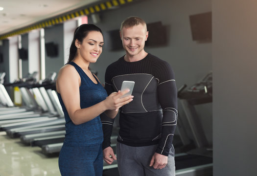 Young couple using smartphone in gym