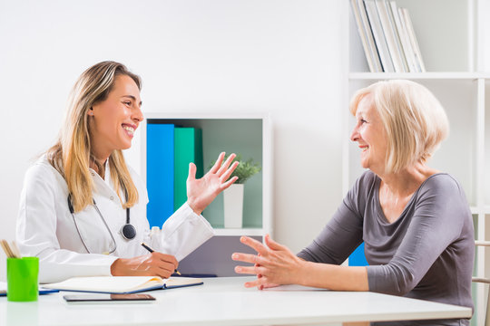 Female doctor and senior woman patient talking in doctor's office.