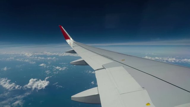 Timelaps : Wing of airplane flying above the clouds. View form the window plane through.