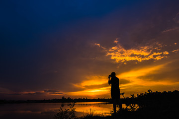 Silhouette photographer at sunset on the lake landscape