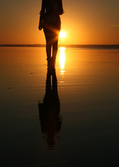 Silhouette of a woman walking towards the camera on a beach at Sunset, Essaouira, Morocco