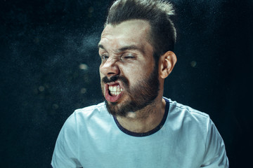 Young handsome man with beard sneezing, studio portrait