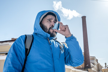 Portrait of young man using asthma inhaler outdoor - obrazy, fototapety, plakaty