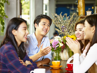 happy young asian adults chatting in coffee shop